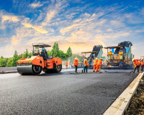 Construction site is laying new asphalt road pavement,road construction workers and road construction machinery scene.highway construction site landscape.